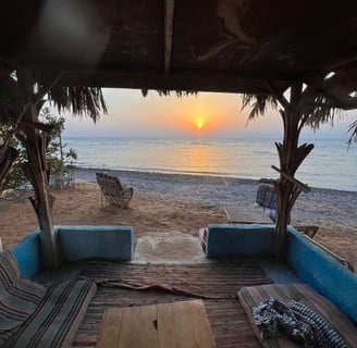 En terrasse til et populært strandrom med en sofa med bord og stoler foran en strand