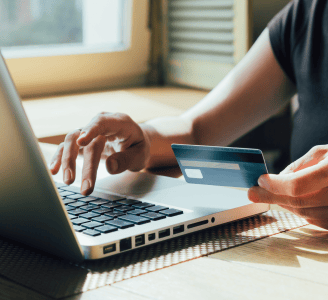 A person using a laptop while holding a credit card, symbolizing online transactions and digital fin