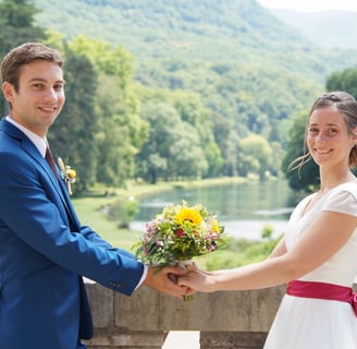 Couple de mariés souriants avec un bouquet champêtre