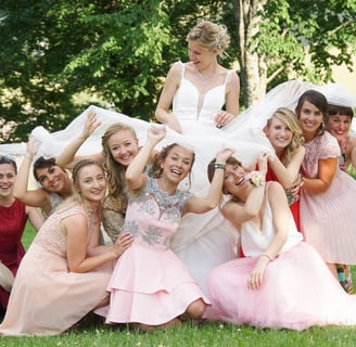 photo de mariée avec ses demoiselles d'honneur souriantes jouant avec et sous sa robe