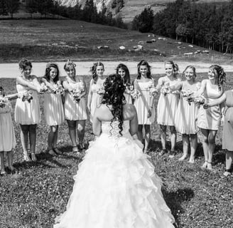 Photo en noir et blanc des demoiselles d'honneur avec des bouquets autour de la mariée