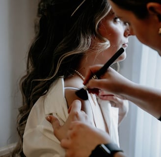 Makeup artist applying makeup to a bride’s shoulders.