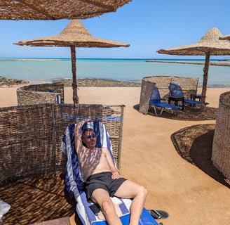 a man laying on a beach chair with a hat on