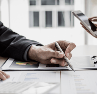 Pessoas analisando gráficos e dados financeiros em reunião, representando organização e planejamento