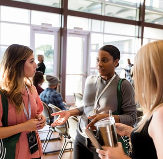 a group of people standing around a table talking at a conference