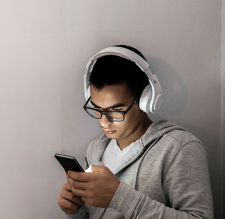a man in a gray hoodie and headphones on a cell phone