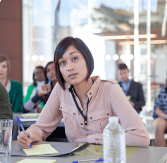 a woman sitting at a table with a notebook and pen