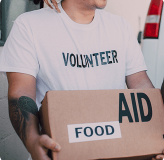 a volunteer in a white shirt is holding a box titled food