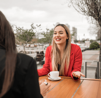 a woman sitting at a table with a cup of coffee