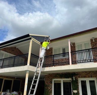 a man in a yellow safety vest is painting a house