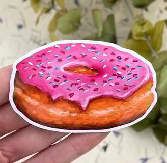 a hand holding a pink donut with sprinkles of sprinkle