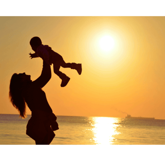 Photo montrant une mère soulevant son enfant sur fond de coucher de soleil
