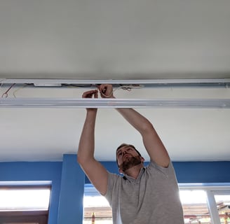 An electrician from Foxley Electrical installing a long light on a ceiling