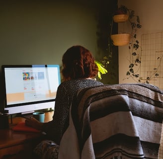 a woman sitting at a desk with a blanket draped over her