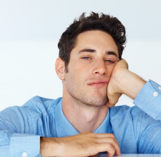 a man sitting at a table with his hand on his chin totally bored