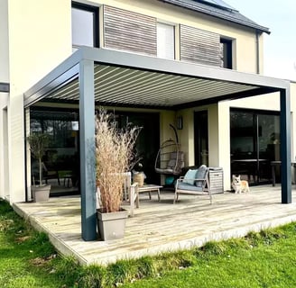 Pergola adossée en aluminium gris installée sur une terrasse moderne avec salon de jardin.