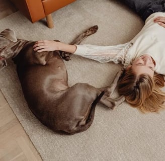 A woman on floor with her dog, thinking about skin disorders in dogs