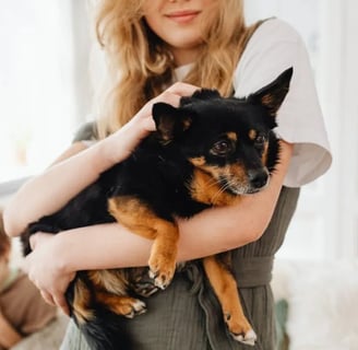 A woman holdong a black puppy