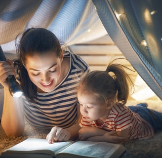 a woman reading a book while her daughter is reading a book