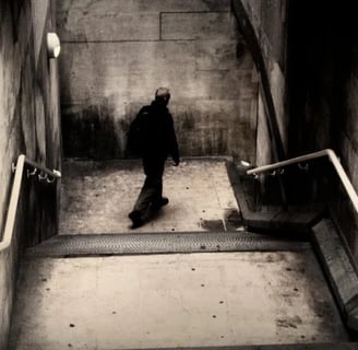 Lone figure walking down a concrete stairwell in a moody urban fine art photograph