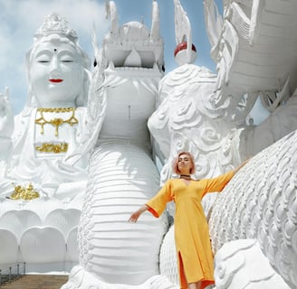 a woman in a yellow dress standing in front of a statue of a dragon