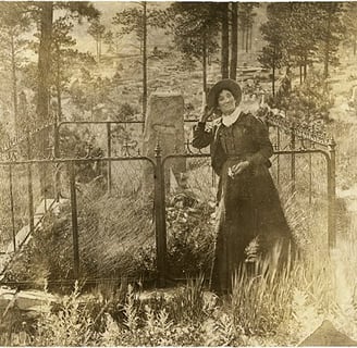 Calamity Jane standing in front of Wild Bill Hickok's grave.