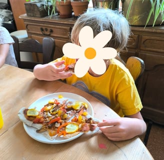 enfant mangeant un pizza cuisinée durant un stage nature et cuisine à Lustin