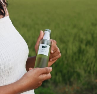 a woman in a white dress holding a bottle of green oil