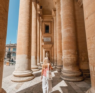 girl walking through mosta rotunda columns