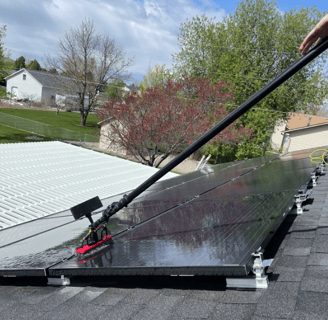 a man using a brush to clean solar panels
