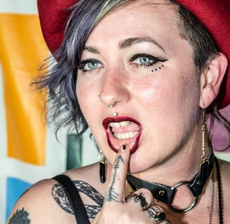 portrait of a girl dressed in a punk style with purple hair with finger on bottom lip daintily