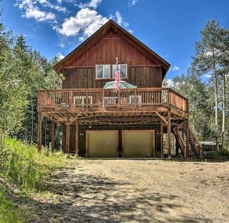 Front view of Moose Creek Lodge cabin with large wooden deck and American flag