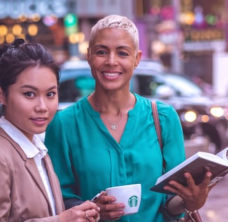two women standing next to each other on a city street
