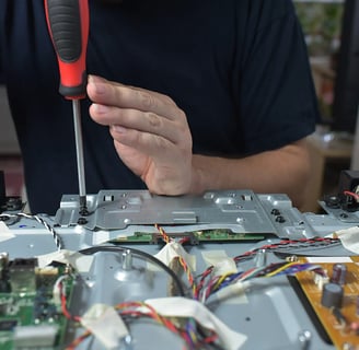 Close-up of hands performing intricate circuit board repair on a TV