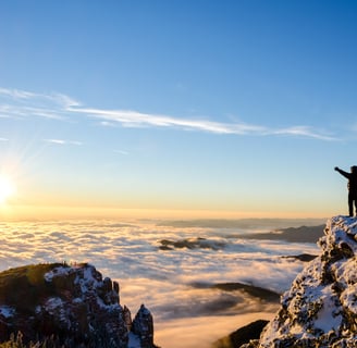 a person standing on a mountain top with arms spread wide