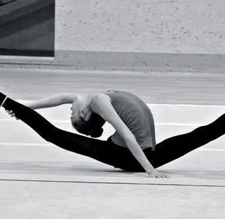 A perfect split of a rhythmic gymnast between two chairs