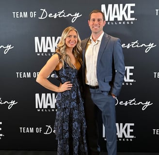 Couple standing in front of Make Wellness backdrop