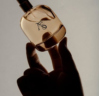 a person holding a bottle of perfume our designer perfumes are here at attarsouq