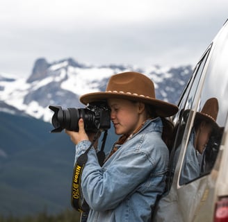 a woman in a hat taking a picture in Banff