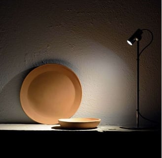 Foco de iluminación puntual destacando elementos decorativos sobre pared de textura natural
