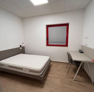 Una habitación con cama doble en el hotel de la escuela de vuelo para el alojamiento confortable de 