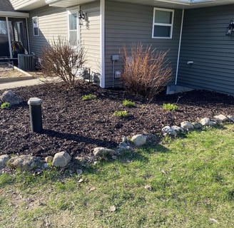 Professional residential landscaping with fresh mulch, trimmed shrubs, and natural stone edging