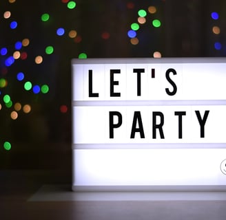 a lit sign reading 'let's party' in a darkened room