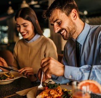 A happy couple enjoying a healthy meal in a restaurant.