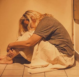 a woman sitting on the floor in a bathroom traumatized