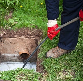 plumber cleaning out a sewer line with a long black hose