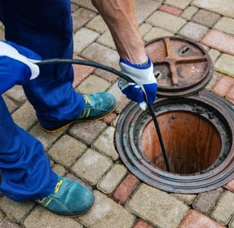 plumber cleaning a sewer line with a hose pump