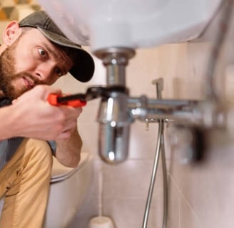 plumber focusing very hard while he is turning a pipe under a sinkj