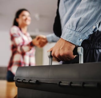 plumber making a deal with a prospect while holding a black tool box