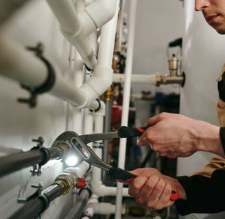 plumber using some channel locks to turn a pipe